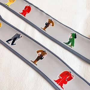 Detail von grauen schmalen Seidenschals mit bunten abstrakten Figuren und Kontrastpaspel