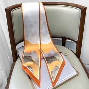 Detail of a slim twilly scarf with abstract orange mountain print on an elegant chair