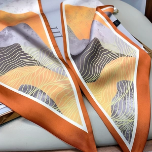 Detail view of abstract orange and grey landscape pattern on a narrow silk scarf