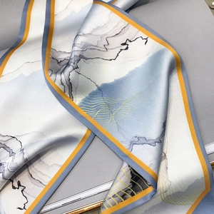 Close-up of silk neck scarf with blue landscape pattern and yellow piping detail