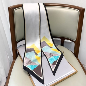 Artistic long silk scarf with mountain print draped on a chair for accessory detail