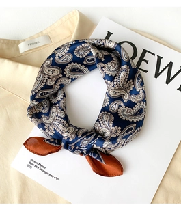 Detailed close-up of paisley silk scarf with navy blue and copper patterns on fabric