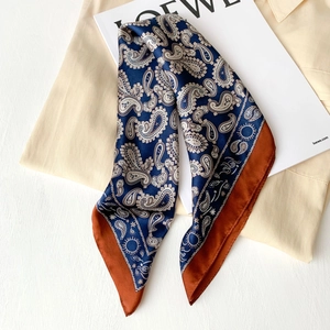Detailed view of paisley silk scarf with deep blue tones and vibrant orange borders