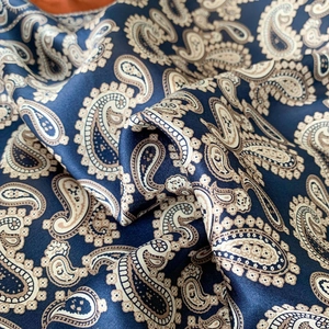 Macro shot of dark blue paisley silk scarf showcasing premium texture and draping