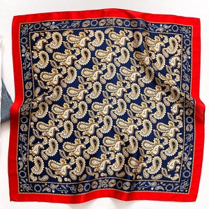 Detailed close-up of paisley pattern silk scarf with dark blue and red border colors