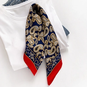 Detail of silk scarf with navy paisley pattern and vibrant red border on white t-shirt