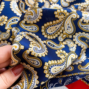 Detailed view of dark blue paisley silk scarf texture with smooth satin finish and drapes