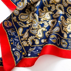 Detail of silk scarf showing navy paisley patterns and contrasting red borders