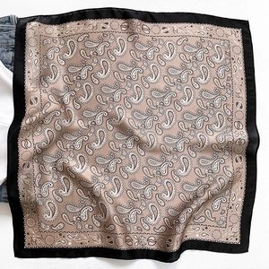 Detailed close-up of silk scarf with paisley patterns and elegant black contrast border
