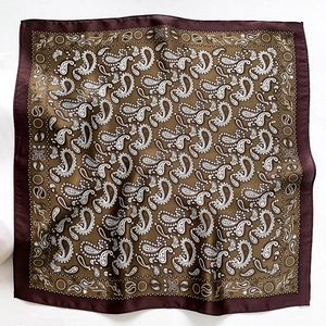 Detail of square silk scarf with vintage olive green paisley pattern and satin finish