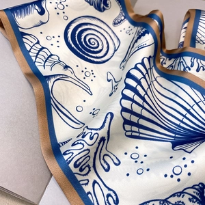 Nahaufnahme des Seidenschals mit Muschelmuster und Korallenprints auf edlem Stoff