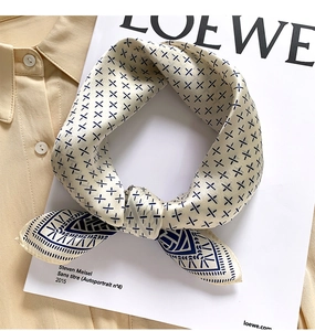 Detailed view of a knotted silk scarf with navy geometric patterns on a beige base