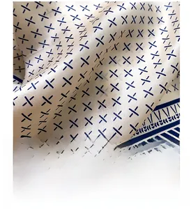 Macro detail of cream silk scarf with dark blue geometric X pattern and smooth texture