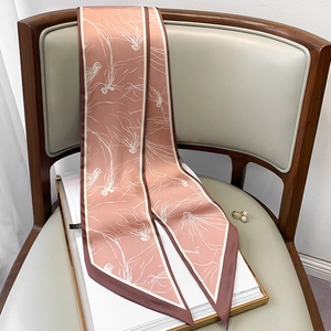 Detail eines staubrosa schmalen Seidenschals mit weißen Blumen auf einem Vintage-Stuhl