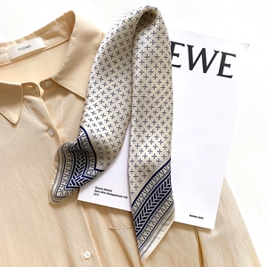 Detail of geometric pattern silk scarf styled on a beige shirt collar