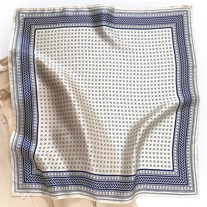 Elegant silk square scarf with navy geometric patterns layered on a white shirt