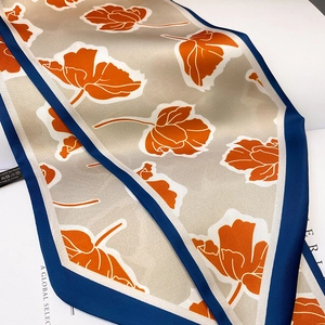 Detailaufnahme von Seidenschal mit Blumenmuster, blauer Kante und glatter Satin-Textur