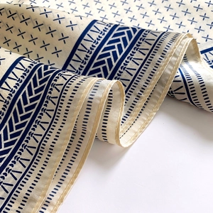 Close-up of silk scarf showing navy geometric patterns and fine edge stitching detail