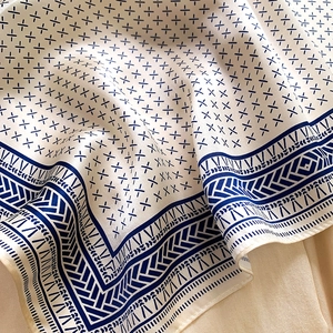 Detailed view of silk square scarf with blue geometric patterns and satin texture