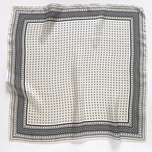 Detailed view of square silk scarf with black geometric patterns on ivory background