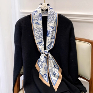 Eleganter weißer Seidenschal mit blauen Meeresmotiven auf schwarzer Strickkleidung