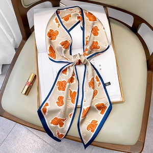 Seidenschal in Champagner mit orangefarbenem Blumendruck als Schleife auf Magazin