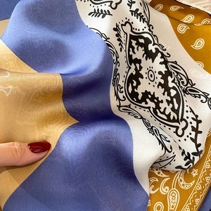 Detailopname van een zijden sjaal met paisley- en bloemmotieven in blauw en geel