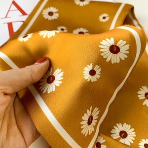 Detail of silk daisy scarf in mustard yellow with floral print and soft texture