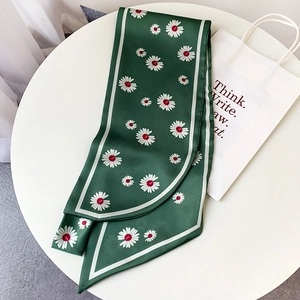 Close-up of elegant dark green daisy print scarf draped on a white minimalist table
