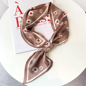 Detail of champagne satin scarf with daisy print tied in a bow on a white book