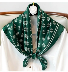 Close-up of a knotted dark green silk scarf with geometric prints on a white shirt