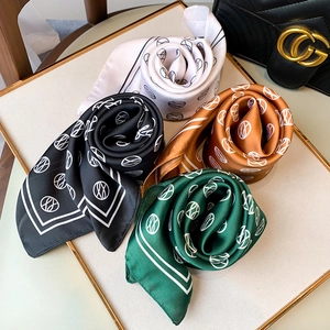 Detailed view of four silk square scarves with geometric prints in a metal display tray
