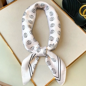 Detail of silk square scarf with geometric logo pattern on elegant display tray