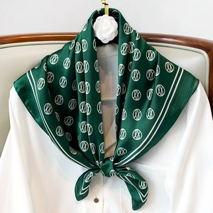 Elegant dark green silk scarf with white geometric patterns styled on a white shirt