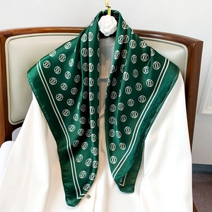 Detail of dark green silk scarf with beige geometric rings on a white shirt