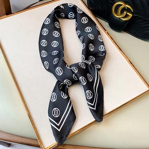 Elegant black silk square scarf with white abstract circle pattern on a luxury tray