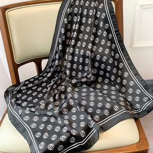 Detailed view of black silk scarf with white geometric patterns draped on a chair