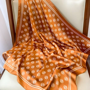 Detail of elegant caramel silk scarf with geometric patterns draped on a white chair