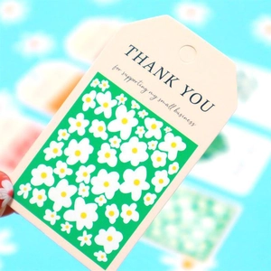 Close-up of floral Thank You tags with daisy patterns for small business packaging