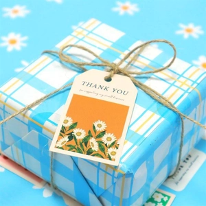 Detail of floral Thank You gift tags with white daisies and natural jute twine on packaging