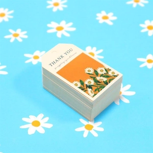 Detail of daisy thank you tags on white paper with twine for small business packaging