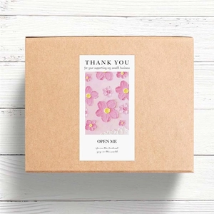 Detail of pink floral Thank You sticker on a brown box for packaging and gift sealing