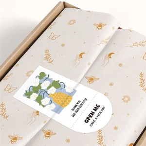 Macro detail of custom packaging with patterned tissue paper and floral thank you sticker