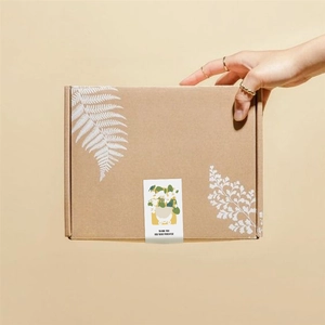 Brown cardboard gift box with botanical stickers and Thank You message held by hand