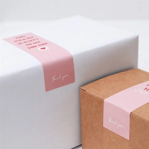 Étiquettes adhésives roses rectangulaires sur boîtes cadeaux avec message merci