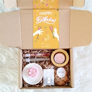 Pink themed birthday gift box with candle, cookies and bath salts on plush rug