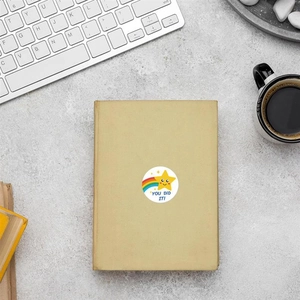 Close-up of You Did It sticker with rainbow and star on an old book cover and desk
