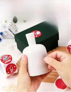 Applying Christmas labels with reindeer and gift box patterns on white ceramic vase