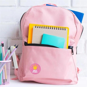 Détail d'un autocollant rose 'Great Effort' avec couronne jaune sur un sac à dos