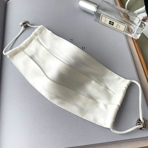 Macro shot of white silk face mask with adjustable elastic ear loops and metal toggles